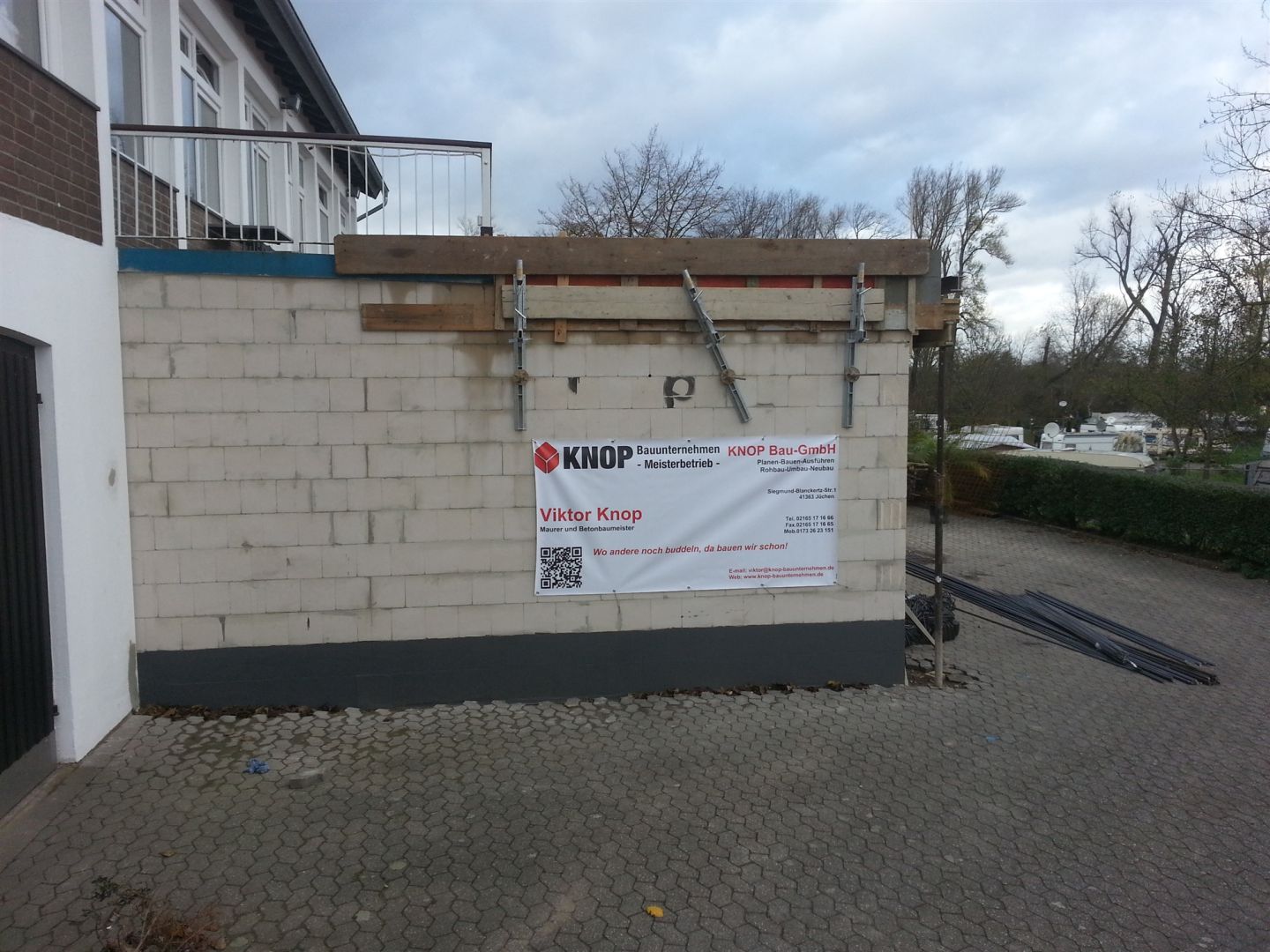 Neu errichtete Mauerwerkswand mit Bauschild von KNOP Bauunternehmen an einem Bestandsgebäude