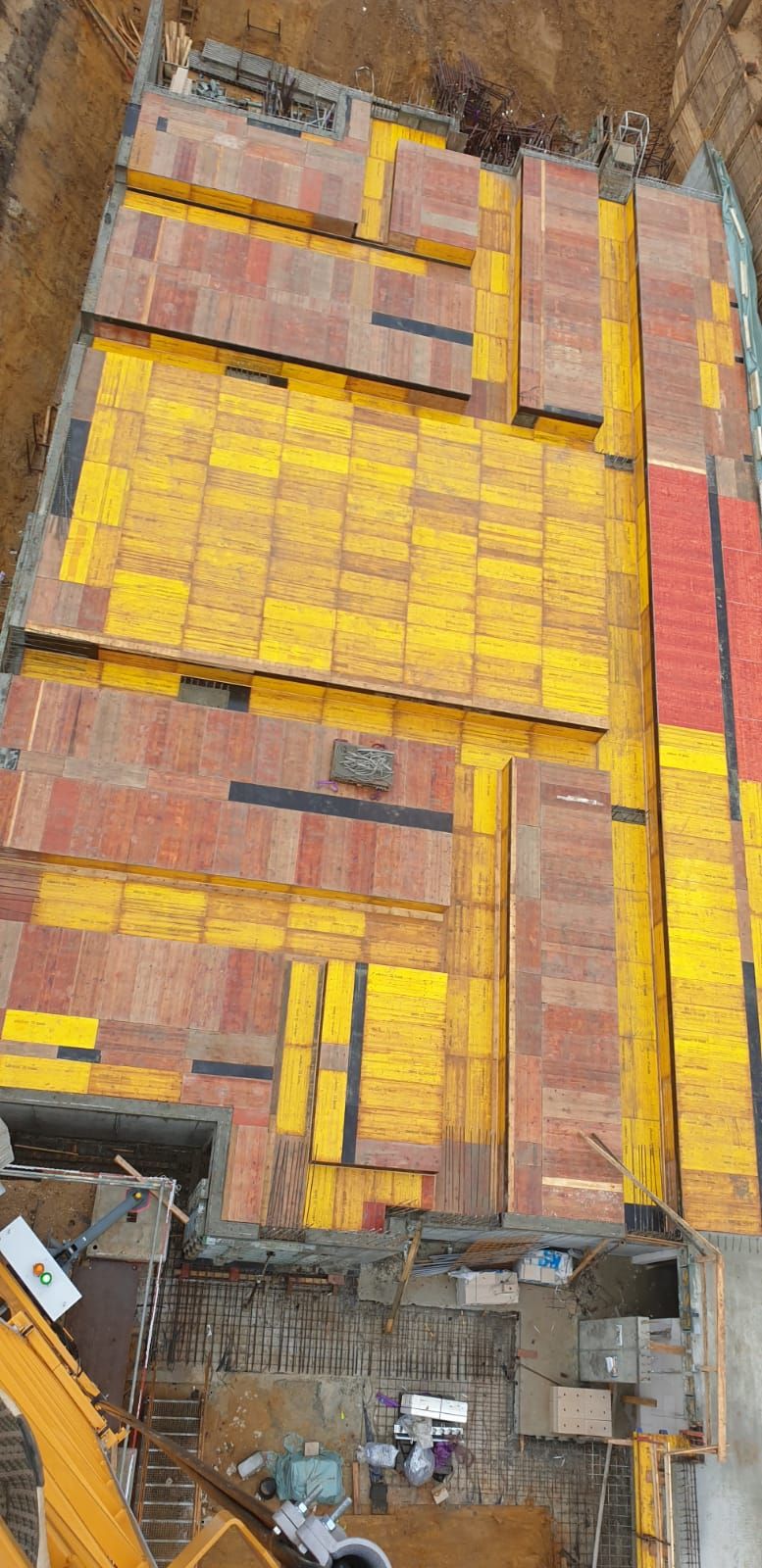 Blick von oben auf eine gelbe Deckenschalung mit Schaltafeln und Aussparungen
